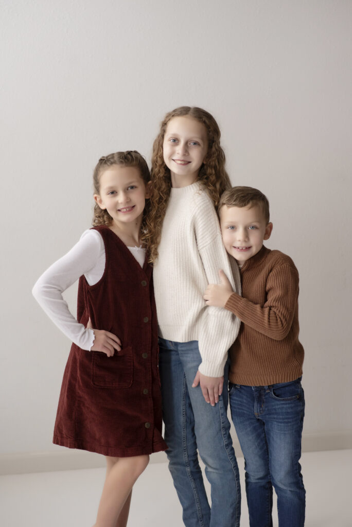 Sweet portrait of three siblings hugging each other during session with Henwood Studios.