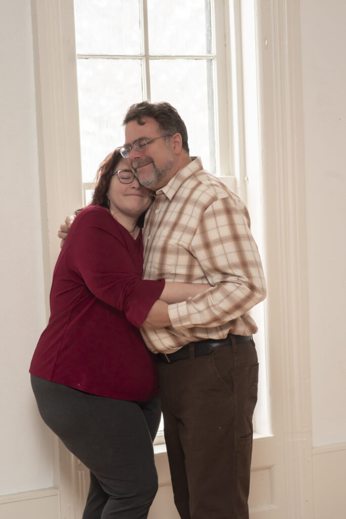 Mom and Dad cozied into each other in front of window.