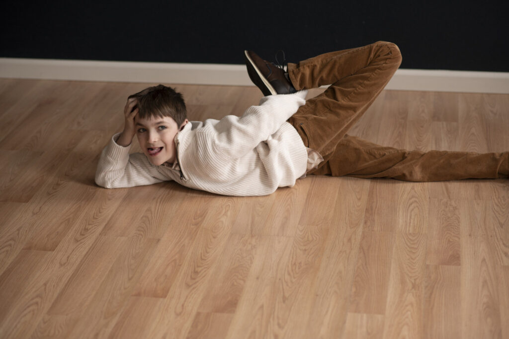 Quirky photo of boy posing on the floor with his leg in the air during family photo session at Henwood Studios.