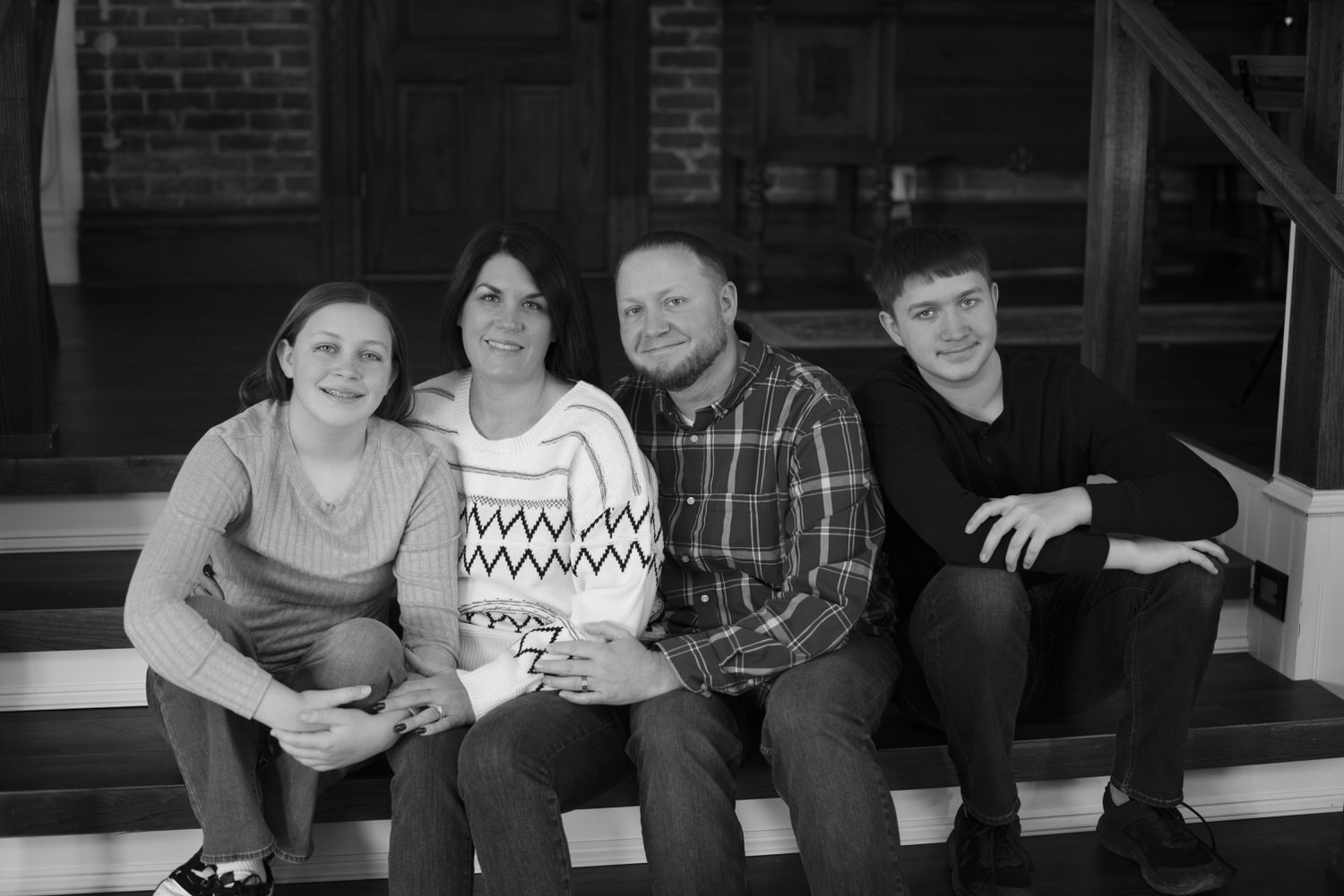 Black-and-white portrait of family sitting on their porch steps during photography session with Henwood Studios.