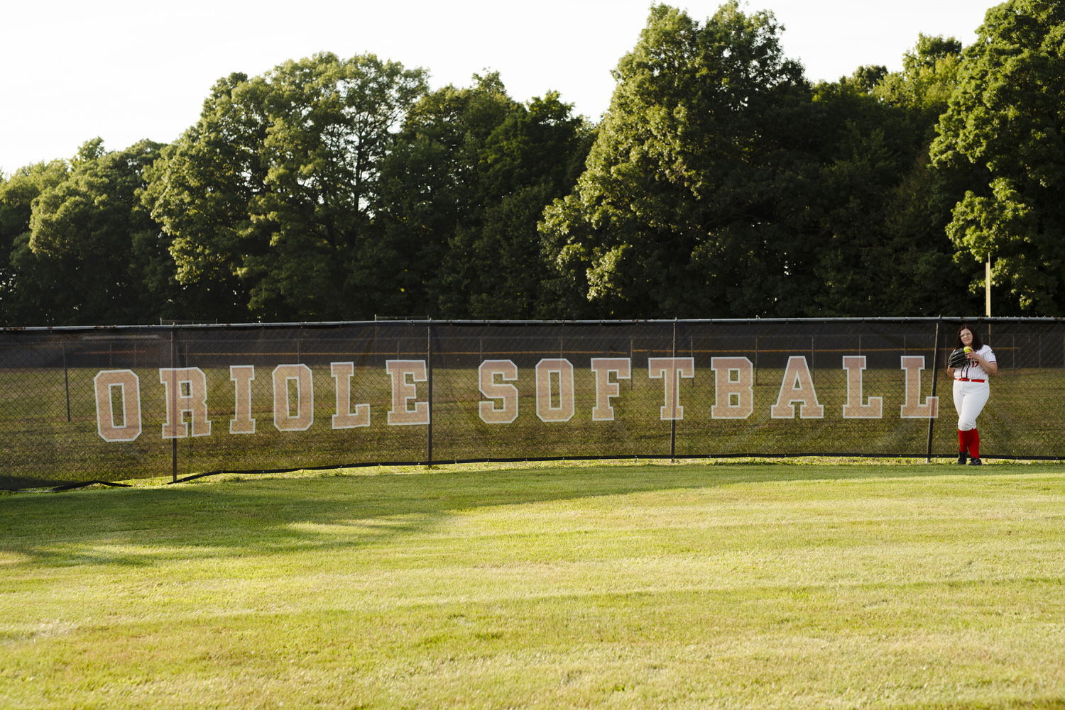 Senior photo of young girl on the Charlotte softball field.