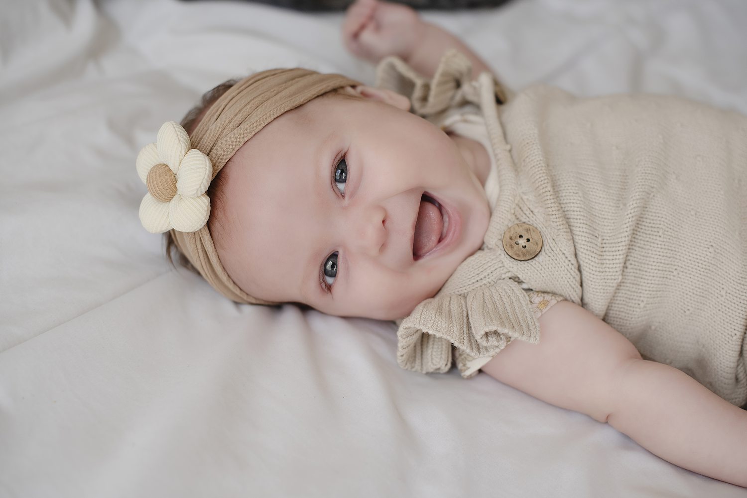 Lively newborn photo of baby girl smiling during studio portrait session with Henwood Studios.
