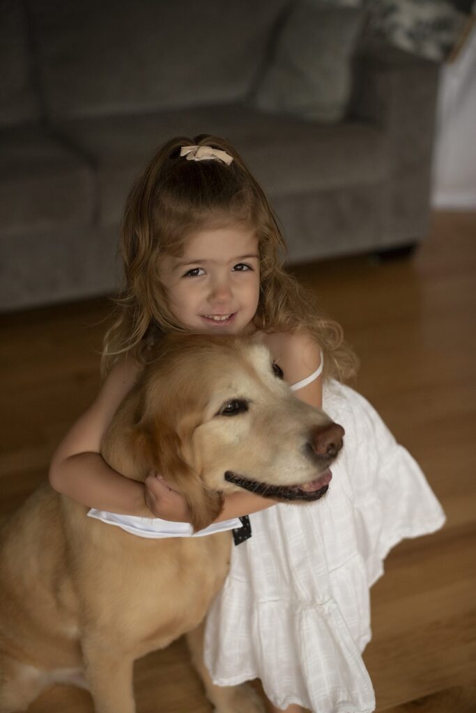 Fun portrait of little girl in a white dress and her dog wearing a tie.