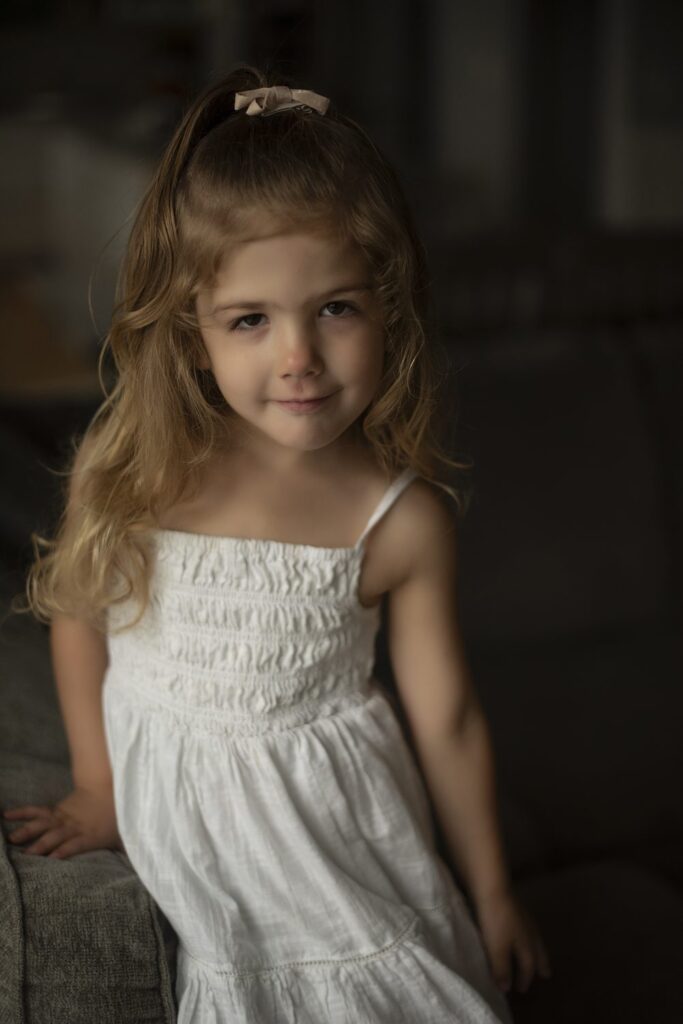 Sassy photo of a little girl wearing a white dress during portrait session with Henwood Sutdios.