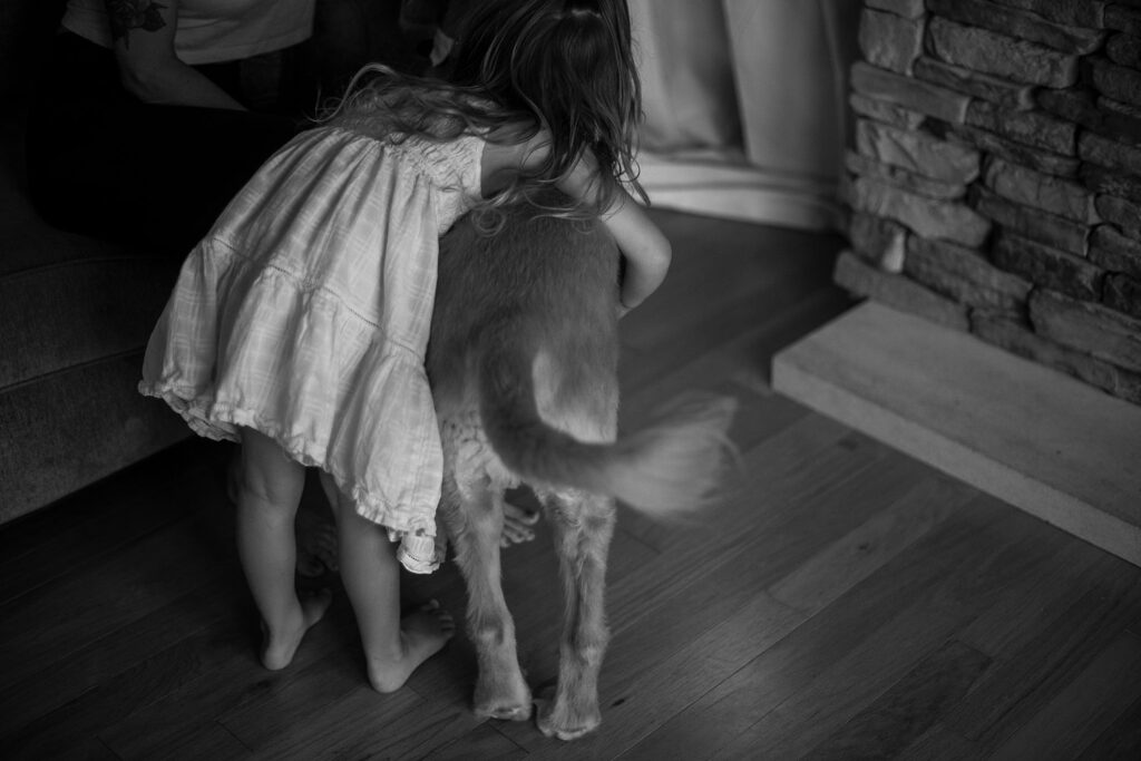 Black-and-white photo of little girl and her dog wagging his tail.