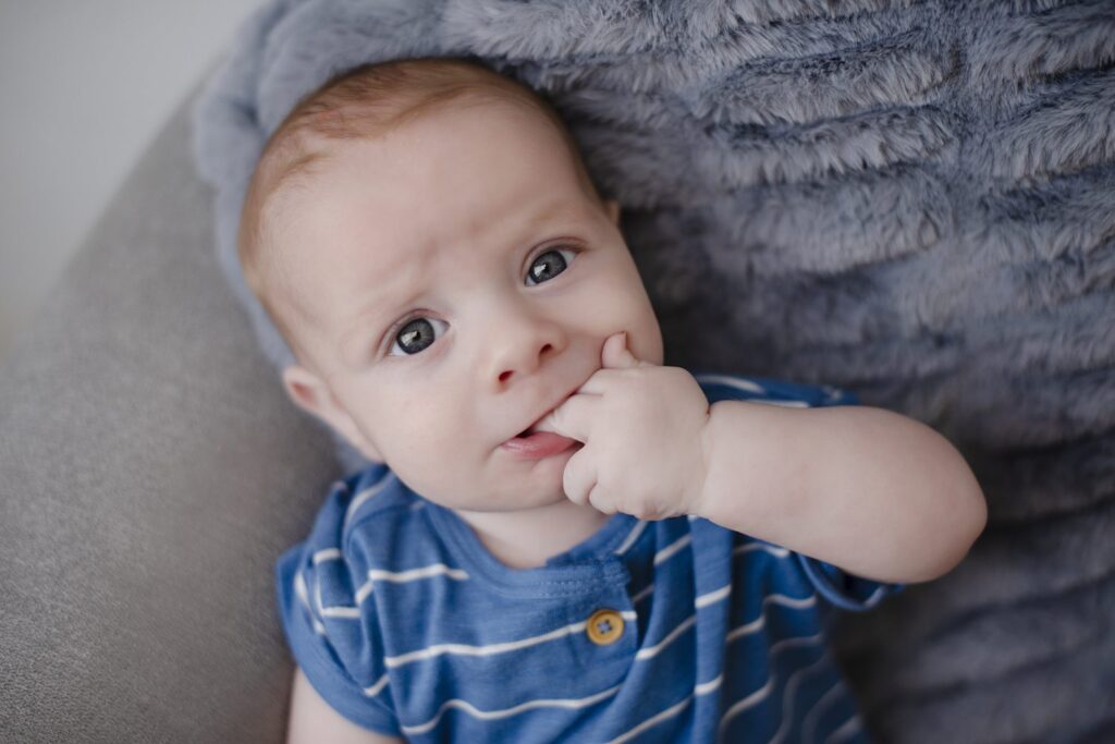 Candid portrait of little boy looking at the camera with his fingers in his mouth during photography session with Henwood Studios.