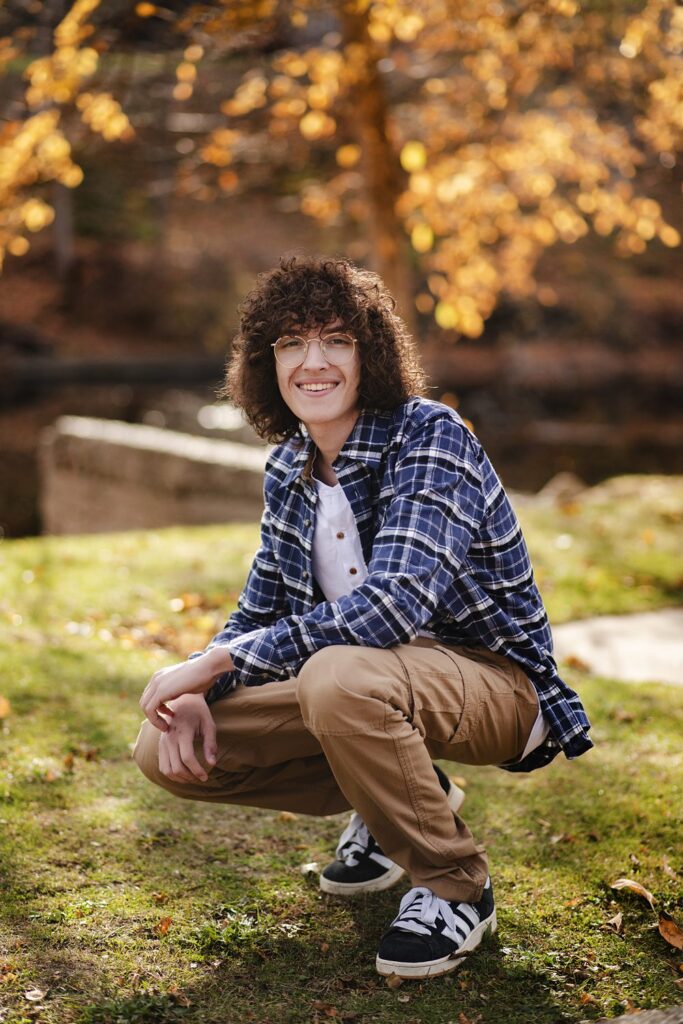 Young man with curly hair photographed outside during Henwood Studio senior photography session.