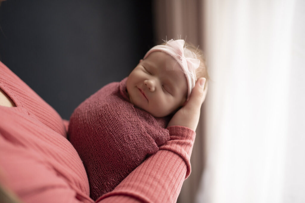 Portrait of newborn baby girl smiling in her mother's arms.