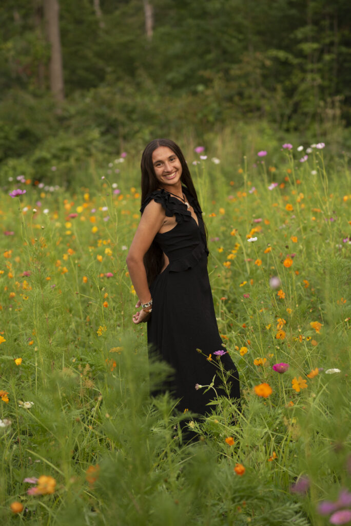 High school senior wearing a black dress smiling at the camera taken by Henwood Studios.
