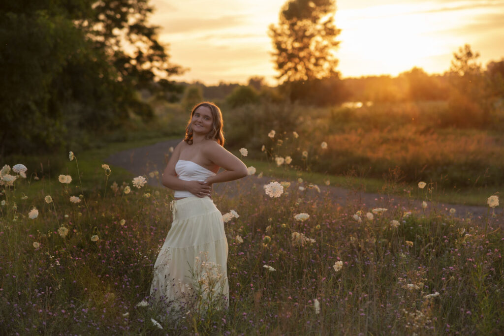 Dreamy sunset portrait of high school senior in a field of flowers taken by Henwood Studios.