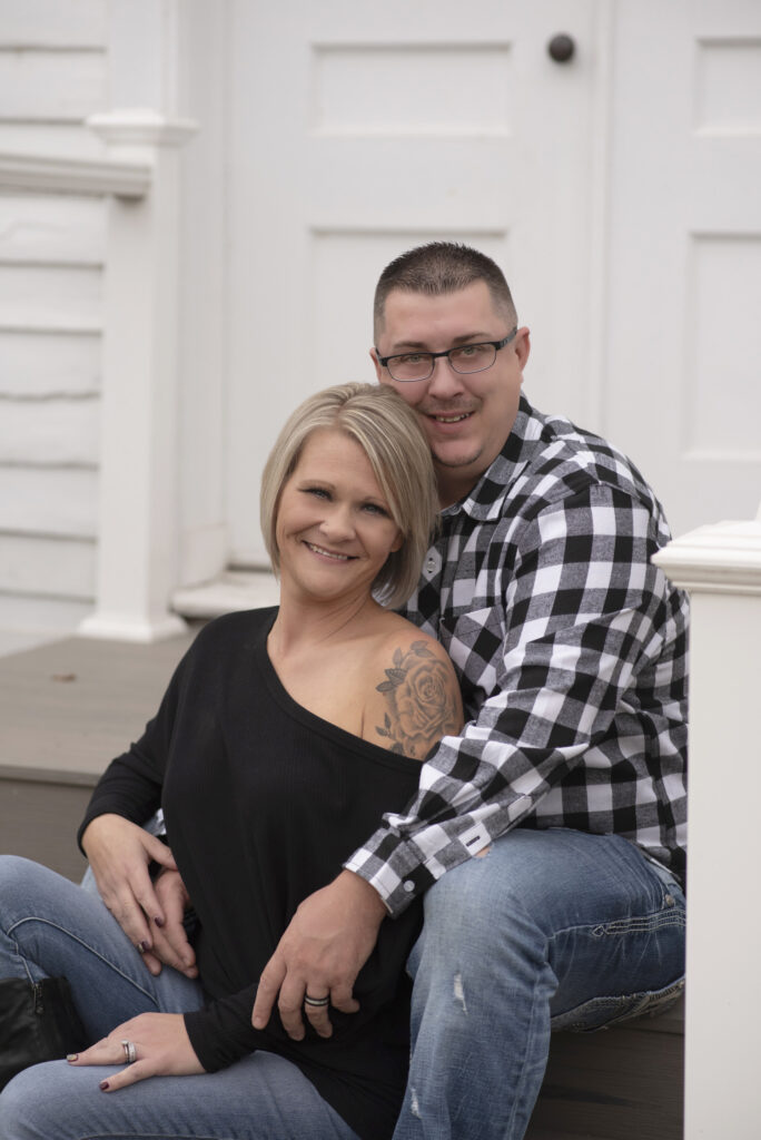 Mom and Dad snuggly seated on courthouse steps during family session with Henwood Studios.