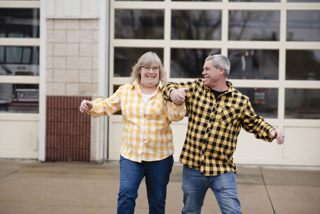 Photo of couple in coordinating plaid shirts dancing outside of the Eaton Rapids Fire Department.