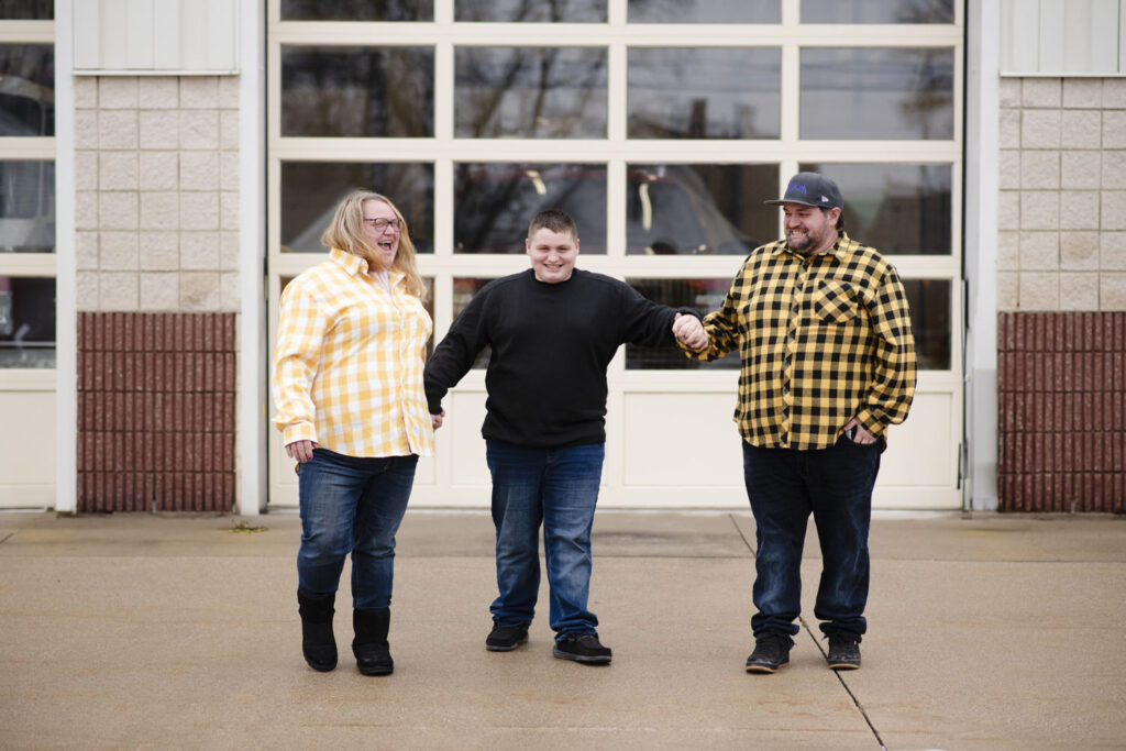 Family joyfully laughing holding hands outside the Eaton Rapids Fire Department.