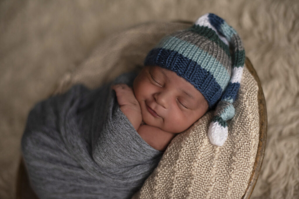 Newborn portrait of baby boy wearing a striped stocking cap.