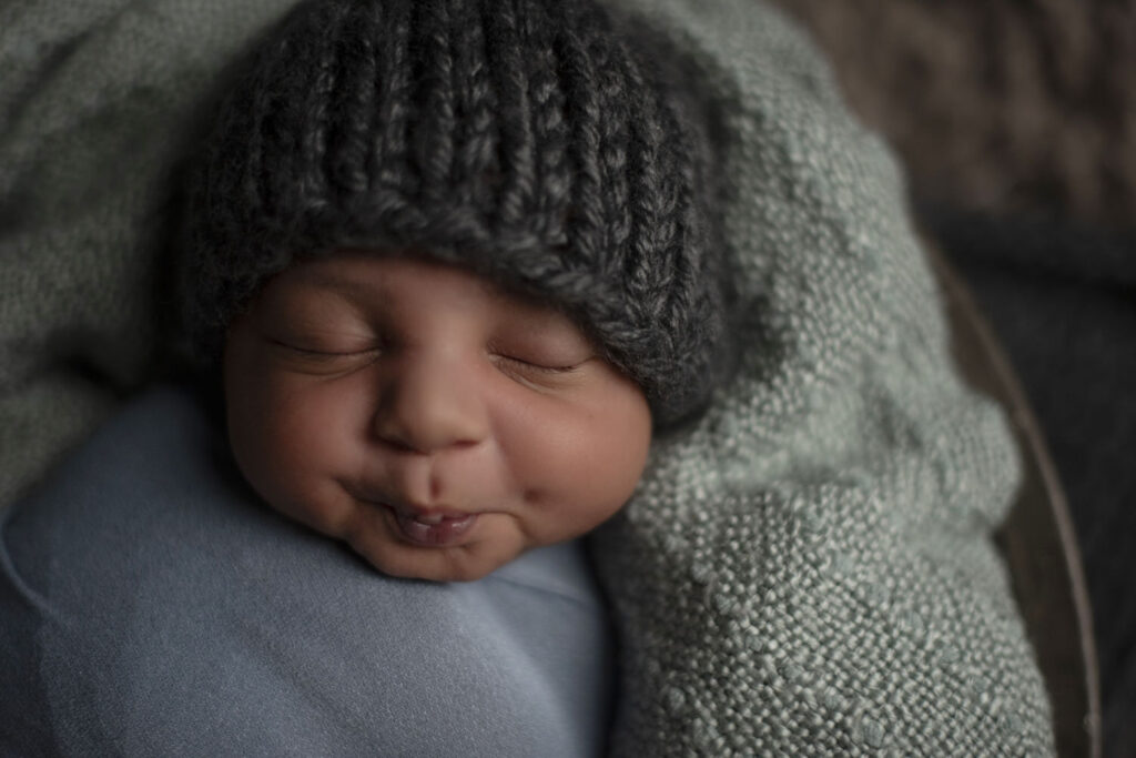 Close up of little newborn boy scrunching his face during session with Henwood Studios.