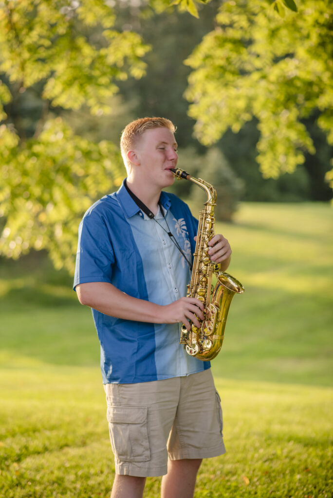 High school senior photographed playing his saxophone outside on the family farm.