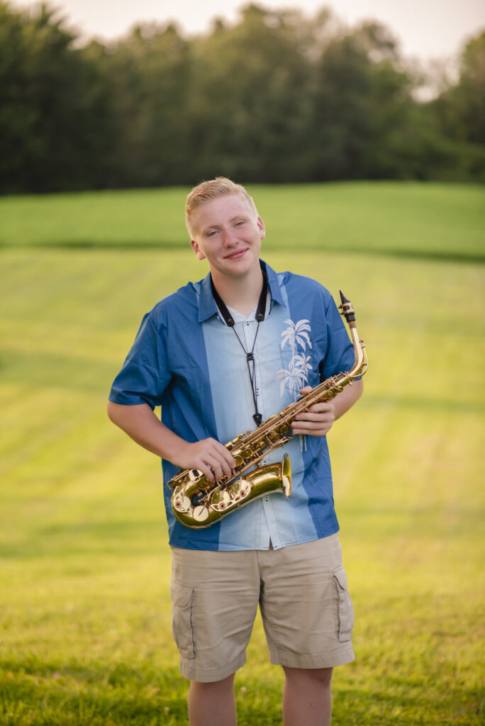 Smiling young man with his saxophone during his senior photo session with Henwood Studios.
