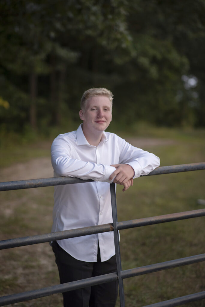 Classic outdoor senior portrait of young man in a white dress shirt photographed on the family farm.